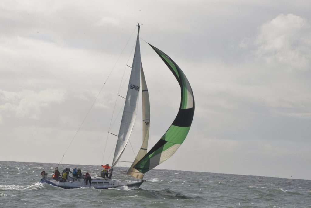 yacht with green spinnaker sailing in choppy conditions