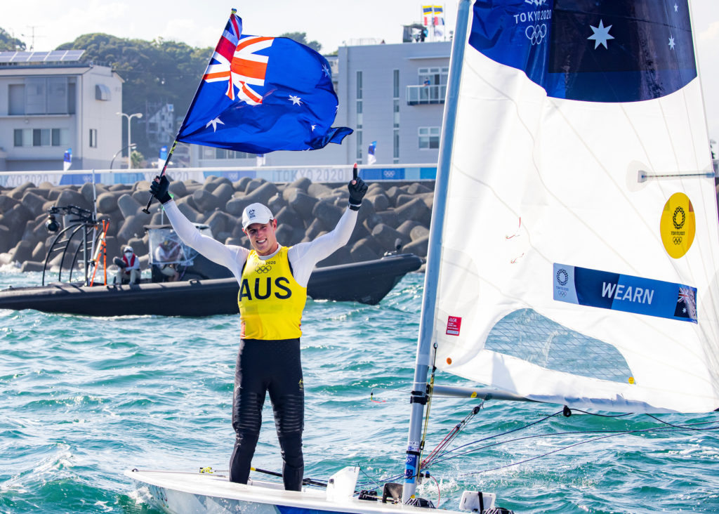 Matt Jerwood holding Australian Flag standing in laser at 2021 Toyko Olympics